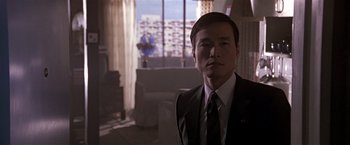 Movie still from “Black Rain” (1989), directed by Ridley Scott – A man wearing a suit and tie in a room; Close Up shot, Low angle