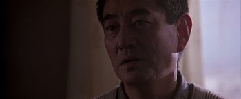 Movie still from “Black Rain” (1989), directed by Ridley Scott – A man's face in a dark room; Close Up shot, Low angle