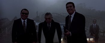 Movie still from “Black Rain” (1989), directed by Ridley Scott – A group of men standing next to each other in front of a bridge; Medium shot, Low angle