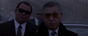 Movie still from “Black Rain” (1989), directed by Ridley Scott – An older man wearing a suit and sunglasses; Close Up shot, Low angle