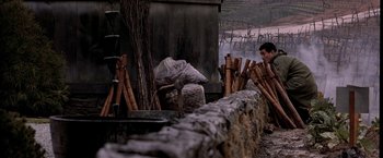 Movie still from “Black Rain” (1989), directed by Ridley Scott – A man standing in front of a pile of wood; Wide shot, Low angle