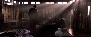 Movie still from “Black Rain” (1989), directed by Ridley Scott – A group of people sitting around a table in a room; Wide shot, High angle