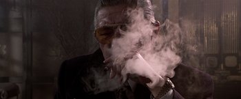 Movie still from “Black Rain” (1989), directed by Ridley Scott – An older man smoking a cigarette in a dark room; Close Up shot, Low angle