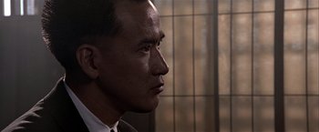 Movie still from “Black Rain” (1989), directed by Ridley Scott – A person wearing a suit and tie; Close Up shot, Over the shoulder angle