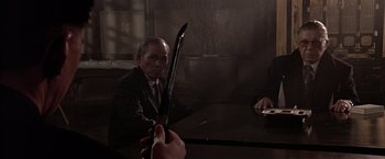 Movie still from “Black Rain” (1989), directed by Ridley Scott – A man in a suit holding a pair of scissors; Medium shot, Over the shoulder angle