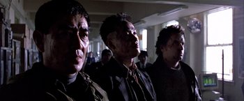Movie still from “Black Rain” (1989), directed by Ridley Scott – A group of men standing next to each other in a room; Close Up shot, Low angle