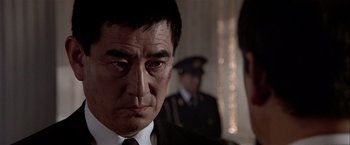 Movie still from “Black Rain” (1989), directed by Ridley Scott – A person wearing a suit and tie; Close Up shot, Over the shoulder angle