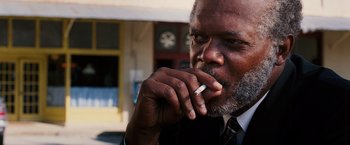 Movie still from “Black Snake Moan” (2006), directed by Craig Brewer – An older man smoking a cigarette while wearing a suit and tie; Close Up shot, Low angle