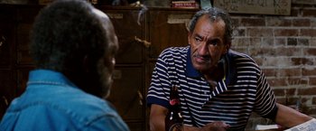 Movie still from “Black Snake Moan” (2006), directed by Craig Brewer – A man sitting in front of another man holding a beer; Close Up shot, High angle