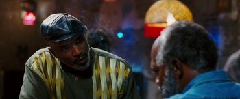 Movie still from “Black Snake Moan” (2006), directed by Craig Brewer – A man with a hat on and smoking a cigarette in front of another man; Close Up shot, Over the shoulder angle