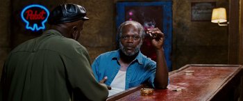Movie still from “Black Snake Moan” (2006), directed by Craig Brewer – An older man sitting at a bar with a cigarette in his hand; Medium shot, Over the shoulder angle