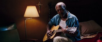 Movie still from “Black Snake Moan” (2006), directed by Craig Brewer – An older man playing an instrument in a room; Medium shot, Low angle