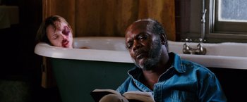Movie still from “Black Snake Moan” (2006), directed by Craig Brewer – An older man sitting in front of a bath tub reading a book; Close Up shot, Over the shoulder angle