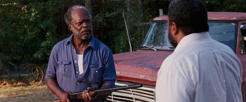 Movie still from “Black Snake Moan” (2006), directed by Craig Brewer – A man holding a rifle in front of a truck; Medium shot, Over the shoulder angle