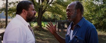 Movie still from “Black Snake Moan” (2006), directed by Craig Brewer – Two men are talking in a field near a fence; Close Up shot, Over the shoulder angle