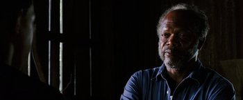 Movie still from “Black Snake Moan” (2006), directed by Craig Brewer – An older black man sitting in front of a wall; Close Up shot, Over the shoulder angle