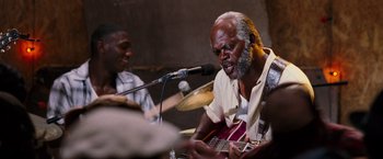 Movie still from “Black Snake Moan” (2006), directed by Craig Brewer – A man with a beard is playing a guitar; Close Up shot, Low angle