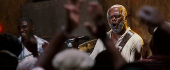 Movie still from “Black Snake Moan” (2006), directed by Craig Brewer – An older man with a beard is singing into a microphone; Close Up shot, Low angle