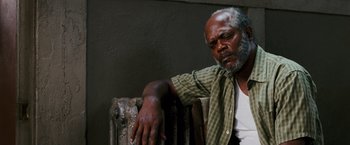 Movie still from “Black Snake Moan” (2006), directed by Craig Brewer – An older man sitting on a chair with his arm resting on a radiator; Close Up shot, High angle