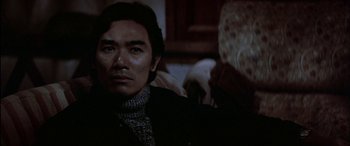 Movie still from “Black Sunday” (1977), directed by John Frankenheimer – A man sitting in front of a camera in a dark room; Close Up shot, Over the shoulder angle
