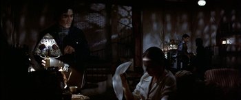 Movie still from “Black Sunday” (1977), directed by John Frankenheimer – A man sitting at a table in front of a woman; Medium shot, Over the shoulder angle