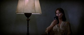 Movie still from “Black Sunday” (1977), directed by John Frankenheimer – A woman holding a camera in front of a lamp; Close Up shot, Low angle