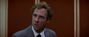 Movie still from “Black Sunday” (1977), directed by John Frankenheimer – A person wearing a suit and tie; Close Up shot, Over the shoulder angle