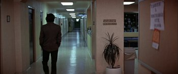 Movie still from “Black Sunday” (1977), directed by John Frankenheimer – A man in a suit walking down a hall way; Wide shot, Over the shoulder angle