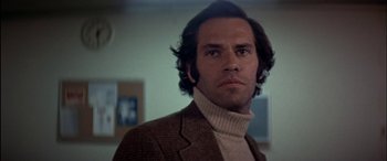 Movie still from “Black Sunday” (1977), directed by John Frankenheimer – A person wearing a suit and a sweater; Close Up shot, Low angle