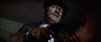 Movie still from “Black Sunday” (1977), directed by John Frankenheimer – A man in a hat and a tie holding a cell phone; Close Up shot, Low angle