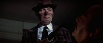 Movie still from “Black Sunday” (1977), directed by John Frankenheimer – A man in a hat holding a rifle; Close Up shot, Low angle