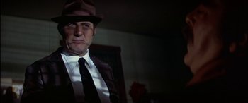 Movie still from “Black Sunday” (1977), directed by John Frankenheimer – A person wearing a hat and a tie; Close Up shot, Low angle