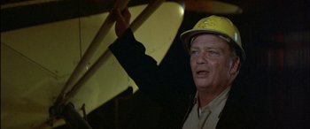 Movie still from “Black Sunday” (1977), directed by John Frankenheimer – An older man wearing a hard hat in a warehouse; Close Up shot, Low angle