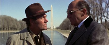 Movie still from “Black Sunday” (1977), directed by John Frankenheimer – Two men standing next to each other near a body of water; Close Up shot, Low angle