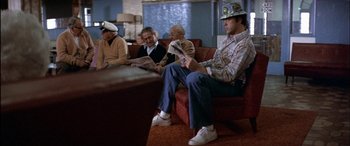 Movie still from “Black Sunday” (1977), directed by John Frankenheimer – A group of people sitting on a couch reading newspapers; Wide shot, High angle