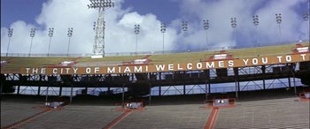 Movie still from “Black Sunday” (1977), directed by John Frankenheimer – An empty bleachers with a sign that reads " welcome to miami "; Extreme Wide shot, Low angle