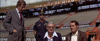Movie still from “Black Sunday” (1977), directed by John Frankenheimer – A man in a suit and a police officer in a uniform; Wide shot, Low angle