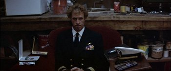 Movie still from “Black Sunday” (1977), directed by John Frankenheimer – A man in a military uniform sitting in an office chair; Medium shot, Low angle