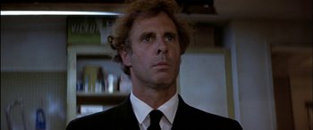 Movie still from “Black Sunday” (1977), directed by John Frankenheimer – A person wearing a suit and tie; Close Up shot, Low angle