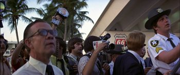 Movie still from “Black Sunday” (1977), directed by John Frankenheimer – A group of people standing next to each other holding cameras; Medium shot, Over the shoulder angle