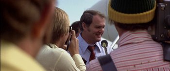Movie still from “Black Sunday” (1977), directed by John Frankenheimer – A man in a red tie talking into a microphone; Close Up shot, Low angle