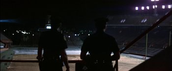 Movie still from “Black Sunday” (1977), directed by John Frankenheimer – Two police officers standing in the dark at night; Extreme Wide shot, Low angle