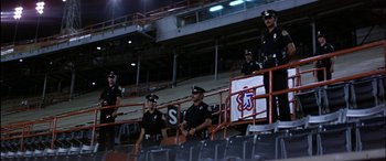 Movie still from “Black Sunday” (1977), directed by John Frankenheimer – A group of police officers standing in a stadium; Extreme Wide shot, High angle