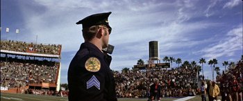 Movie still from “Black Sunday” (1977), directed by John Frankenheimer – A police officer standing in front of a crowd of people; Wide shot, Low angle