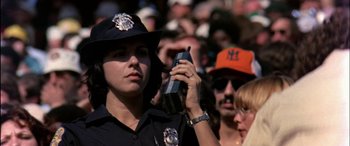 Movie still from “Black Sunday” (1977), directed by John Frankenheimer – A police officer holding a cell phone in front of a crowd of onlookers; Close Up shot, Low angle