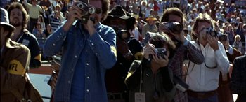 Movie still from “Black Sunday” (1977), directed by John Frankenheimer – A group of people taking pictures of a crowd of onlookers; Medium shot, High angle