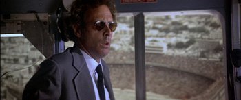 Movie still from “Black Sunday” (1977), directed by John Frankenheimer – A man in a suit and sunglasses looking out of a window; Close Up shot, Low angle