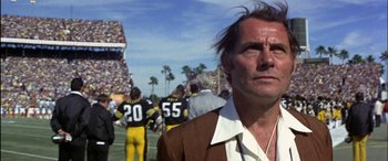 Movie still from “Black Sunday” (1977), directed by John Frankenheimer – A man standing on top of a football field next to a crowd; Close Up shot, Low angle
