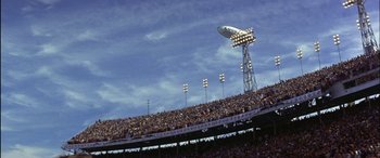Movie still from “Black Sunday” (1977), directed by John Frankenheimer – A crowd of people in stands at a stadium; Extreme Wide shot, Low angle