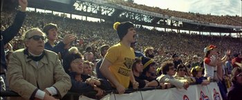 Movie still from “Black Sunday” (1977), directed by John Frankenheimer – A group of people that are standing in a stadium; Medium shot, High angle